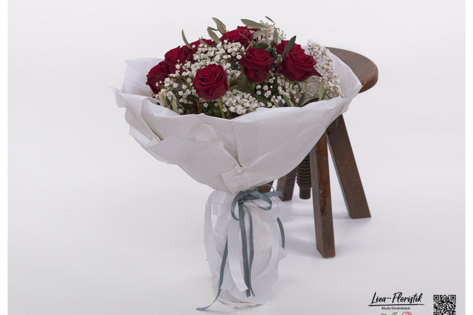 Rote Rosen in Manschette gewickelt mit Olivenzweigen und weißem Schleierkraut
