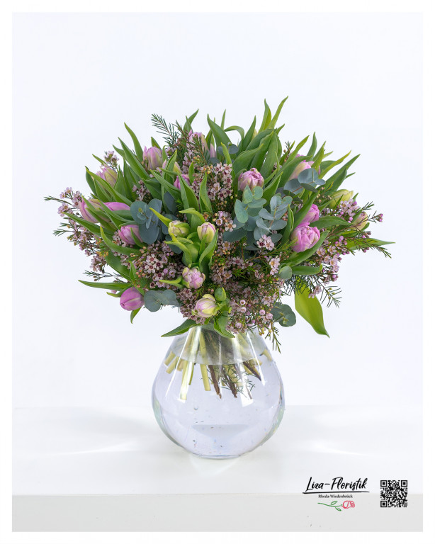 Blumenstrauß mit lila Tulpen, zarten Wachsblumen und Eukalyptuszweigen, arrangiert mit frischem Grün.