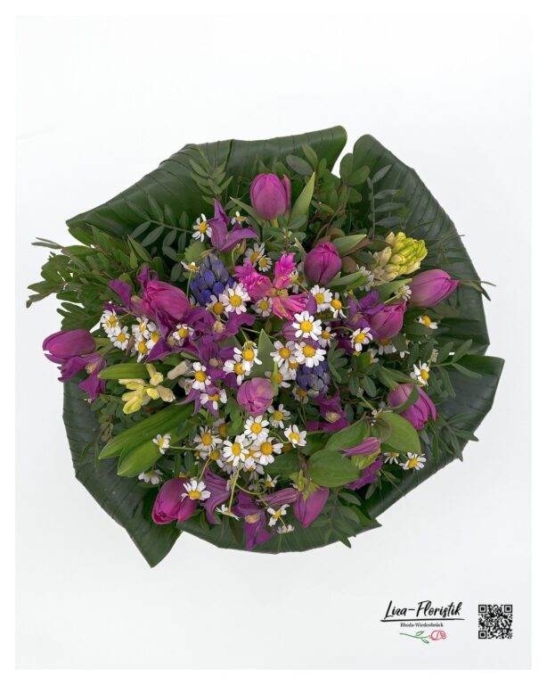 Der Frühlingsstrauß aus leuchtenden lila Tulpen, strahlend weißen Kamillenblüten, duftenden Hyazinthen, hellgelben Narzissen und zarten grünen Blättern präsentiert sich aus einer anderen Perspektive besonders harmonisch und lebendig.