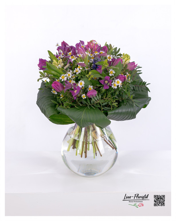 Ein wunderschöner Frühlingsstrauß aus lila Tulpen, strahlend weißen Kamillenblüten, duftenden Hyazinthen, hellgelben Narzissen und zarten grünen Blättern, der eine harmonische und ansprechende Komposition bildet.