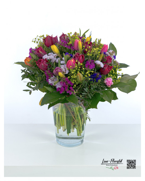 Ein lebendiger Frühlingsstrauß mit einer harmonischen Mischung aus roten, gelben und rosa Tulpen, zarten Schleierkraut-Blüten, violetten Statice, leuchtendem Frauenmantel und sattgrünem Eukalyptus – ein farbenfrohes Arrangement voller Frische und Lebensfreude.
