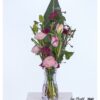 Moderner Blumenstrauß mit rosa Ranunkeln, violetten Nelken, gefärbtem Ammi und zarten Tulpen, kombiniert mit dekorativen Kirschzweigen und einem großen Strelitzienblatt als Hintergrund.