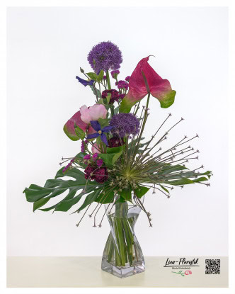 Moderner Blumenstrauß mit Allium, darunter auch eine sternförmig explodierende Allium-Schuberti-Blüte. Ergänzt wird das Arrangement durch leuchtend pinke Anthurien, zarte rosa Pfingstrosen, tiefviolette Clematis und kleine, filigrane Statice-Blüten – kombiniert mit großflächigem Grün für einen expressiven, skulpturalen Look.