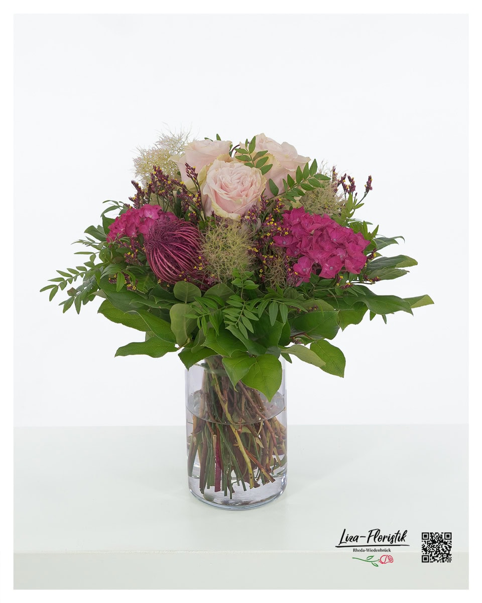Blumenstrauß mit pinken Hortensien, zartrosa Ecuador Rosen der Sorte Pink Mondial, gefärbtem Ami, violetter Statice und luftigem Perückenstrauch, umgeben von kräftigem Grün.