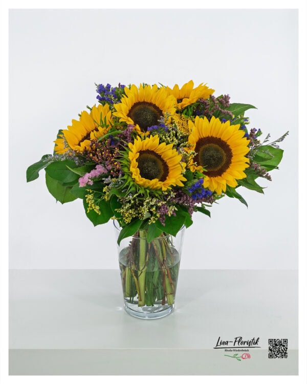 Sommerlicher Blumenstrauß mit leuchtenden Sonnenblumen, begleitet von verschiedenen Statice-Sorten in Lila, Rosa und Blau sowie frischem Grün aus Pistazie und Salal. Sommerlicher Blumenstrauß mit leuchtenden Sonnenblumen, begleitet von verschiedenen Statice-Sorten in Lila, Rosa und Blau sowie frischem Grün aus Pistazie und Salal.