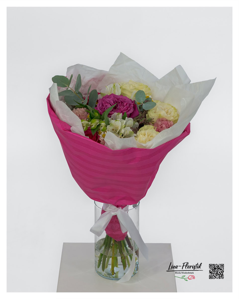 Blumenstrauß mit verschiedenen Rosen, Nelken, Lisianthus, Kamille und Eukalyptus, dekorativ gebunden und in pinkfarbener Manschette arrangiert.