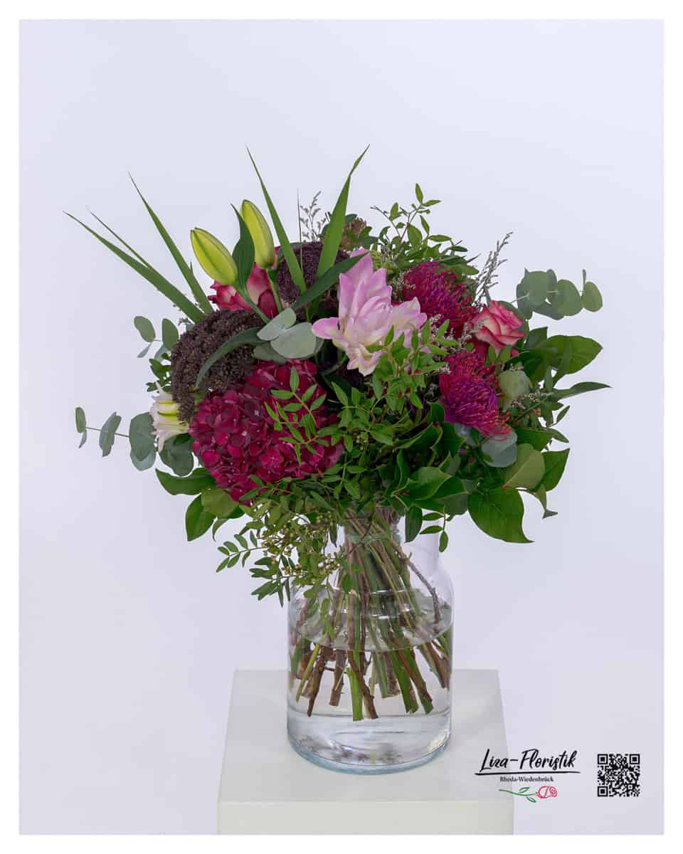 Opulenter Blumenstrauß mit Rosen, Celosien, Angelica Giga, Nadelkissenprotea, Lilien und Eukalyptus – elegant gebunden in harmonischen Farben.