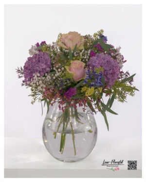 Imposanter Blumenstrauß mit Rosen, violetten Hortensien, luftigem Schleierkraut, Eukalyptus, Statice, Disteln und leuchtendem Rittersporn.