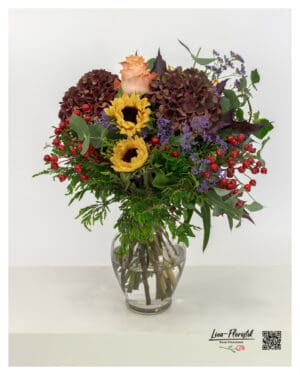 Herbstlicher Strauß mit bordeauxfarbenen Hortensien, gelben Sonnenblumen, Protea, apricotfarbenen Rosen, Statice, Eukalyptus, Hagebutten und dunkelviolettem Laub