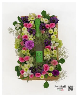 Blumengesteck in rustikaler Holzkiste mit Sekt, rosa Rosen, violetten Blüten, cremeweißen Santini und zartem Perückenstrauch